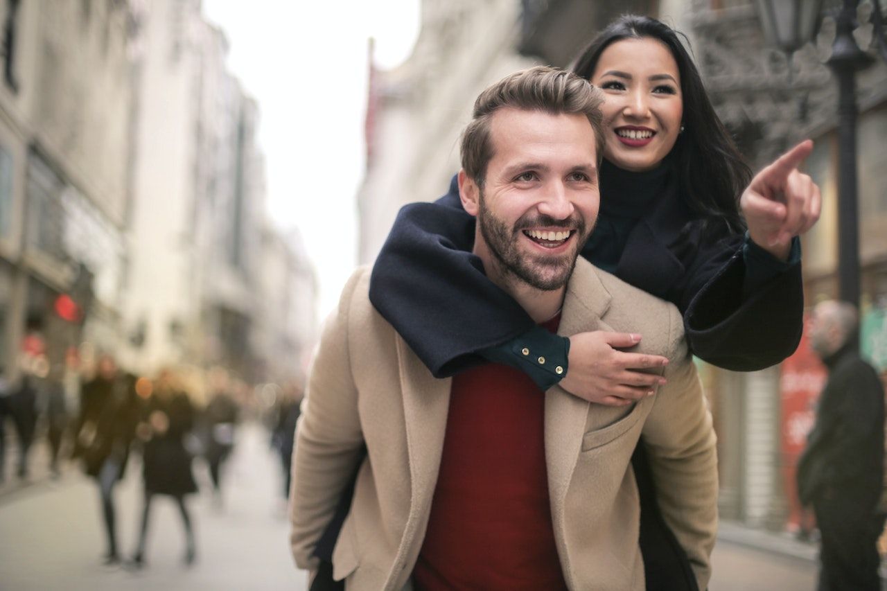Couple having giving a piggy back and thinking about all-inclusive or a traditional surrogacy agency