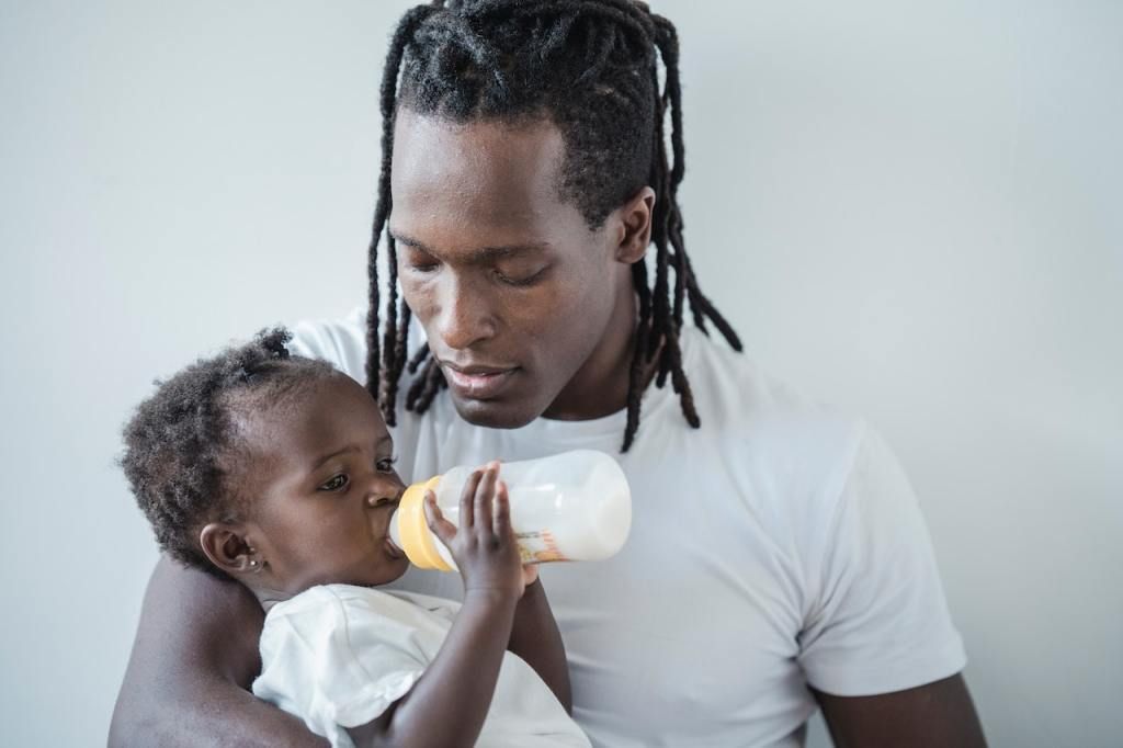 Black man feeding his baby through surrogacy breastmilk