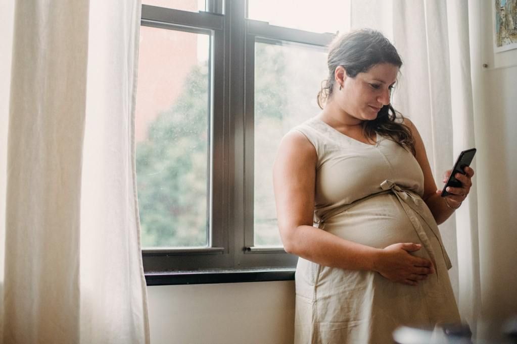 Pregnant surrogate mother texting with intended parents